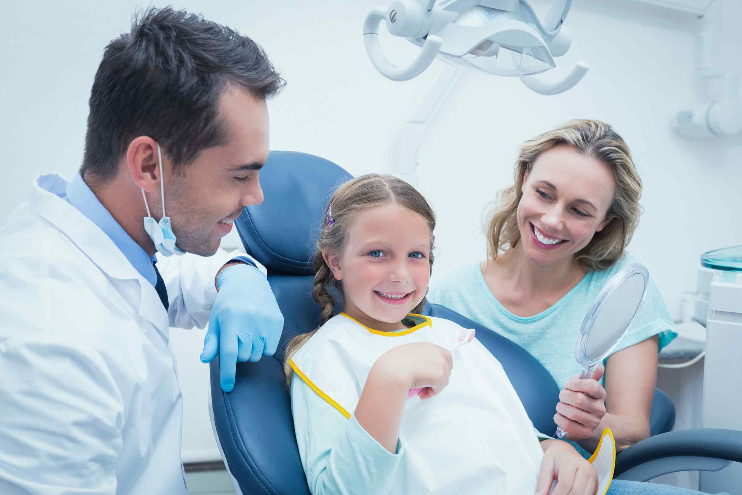 dentist with child patient and mother